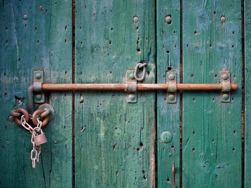 porte verte fermée par un vieux cadenas
